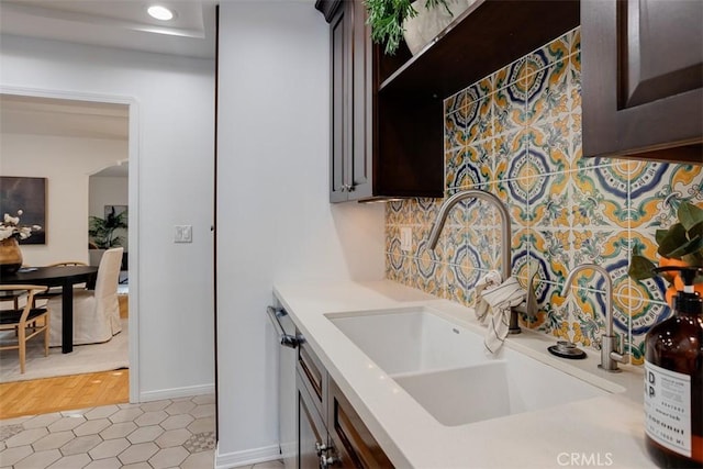 kitchen featuring sink, decorative backsplash, dark brown cabinets, and light tile patterned floors