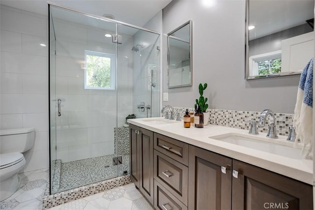 bathroom featuring tasteful backsplash, vanity, a shower with door, and toilet