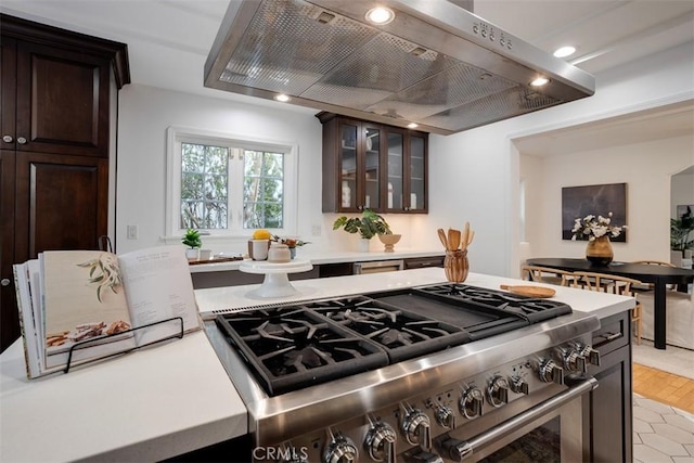 kitchen featuring dark brown cabinets, exhaust hood, high end stainless steel range oven, and light tile patterned flooring