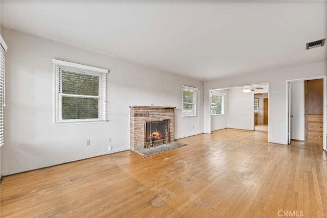 unfurnished living room with ceiling fan, a fireplace, and light hardwood / wood-style floors