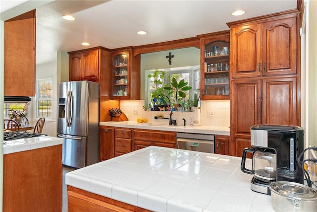 kitchen with stainless steel appliances, tasteful backsplash, sink, and tile countertops