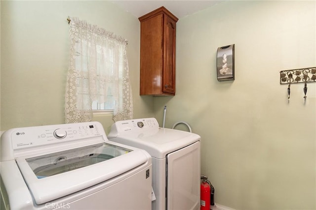 clothes washing area with separate washer and dryer and cabinets