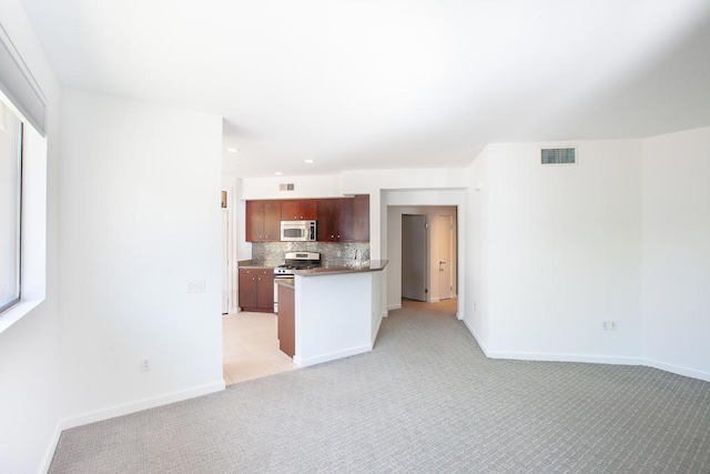 kitchen featuring backsplash, light colored carpet, kitchen peninsula, and appliances with stainless steel finishes