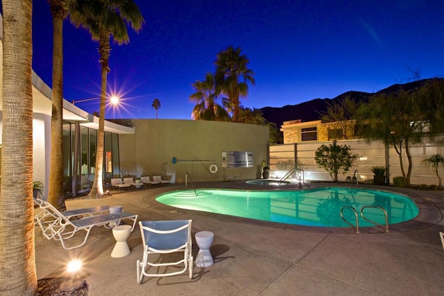 pool at twilight featuring a patio and a mountain view