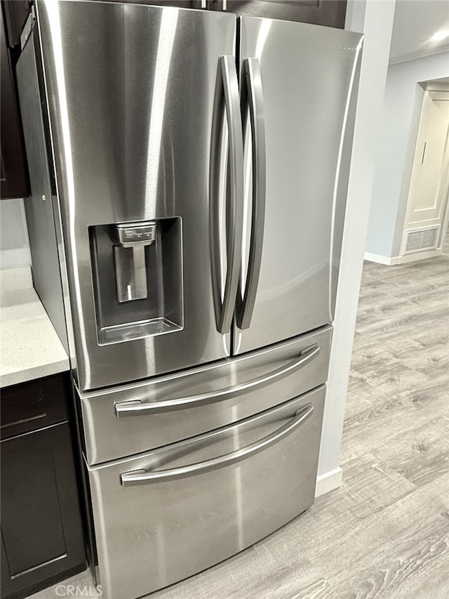 interior details featuring crown molding, light hardwood / wood-style flooring, and stainless steel refrigerator with ice dispenser