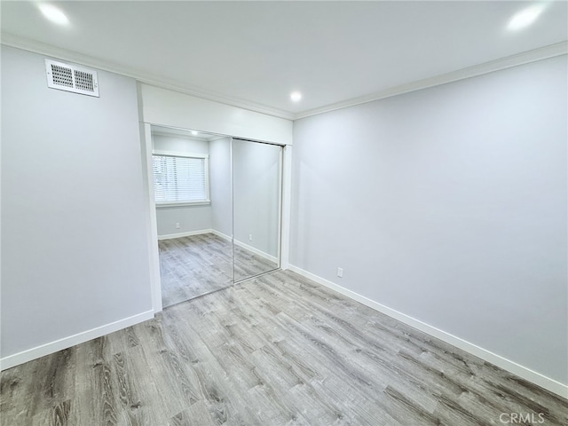 unfurnished bedroom featuring ornamental molding, a closet, and light wood-type flooring