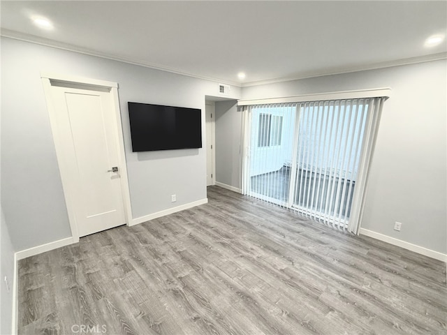 spare room featuring ornamental molding and light hardwood / wood-style floors