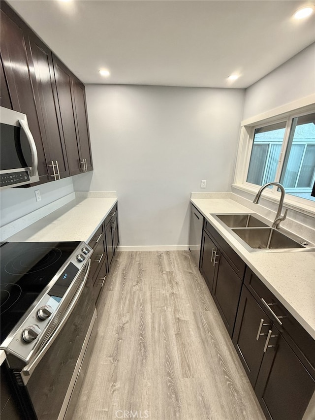 kitchen with dark brown cabinetry, sink, stainless steel appliances, and light hardwood / wood-style floors