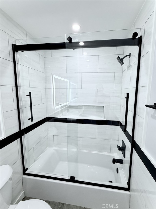 bathroom featuring toilet and combined bath / shower with glass door