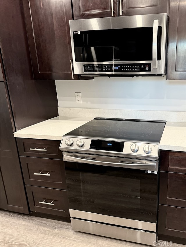 kitchen with dark brown cabinetry and appliances with stainless steel finishes