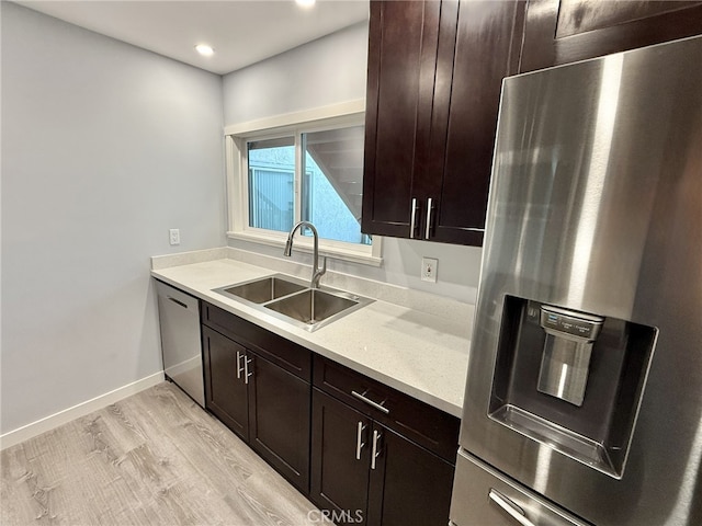 kitchen featuring stainless steel appliances, dark brown cabinets, sink, and light hardwood / wood-style flooring