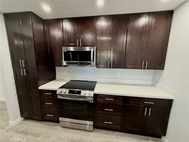 kitchen featuring stainless steel appliances, dark brown cabinets, and light wood-type flooring