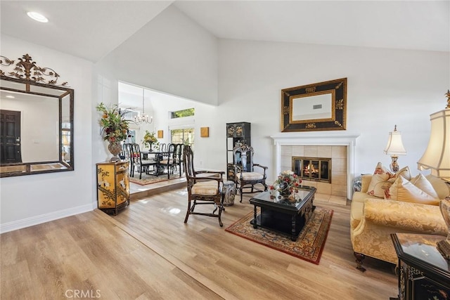 living room with hardwood / wood-style floors, a fireplace, high vaulted ceiling, and a chandelier