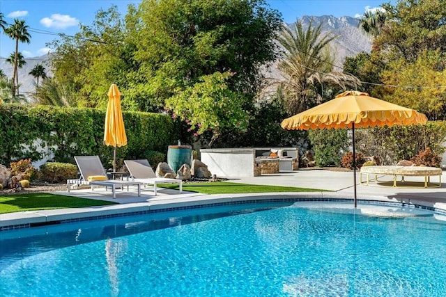 view of pool with a patio, an outdoor kitchen, and a mountain view