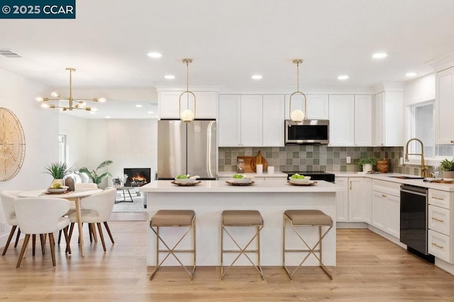 kitchen with pendant lighting, white cabinetry, a kitchen island, and appliances with stainless steel finishes