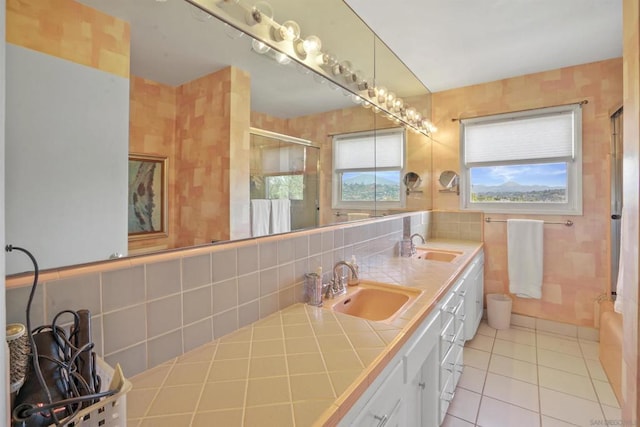 bathroom featuring vanity, a shower with shower door, tile patterned floors, and tile walls