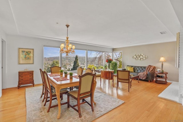 dining area with an inviting chandelier and light hardwood / wood-style flooring