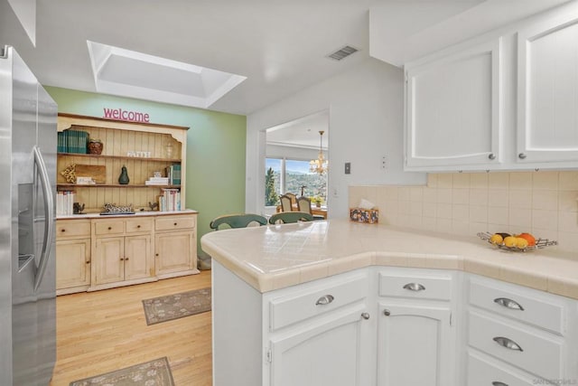 kitchen featuring kitchen peninsula, white cabinets, and stainless steel fridge with ice dispenser