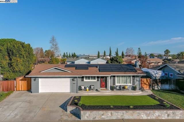 single story home with a garage, a front yard, and solar panels