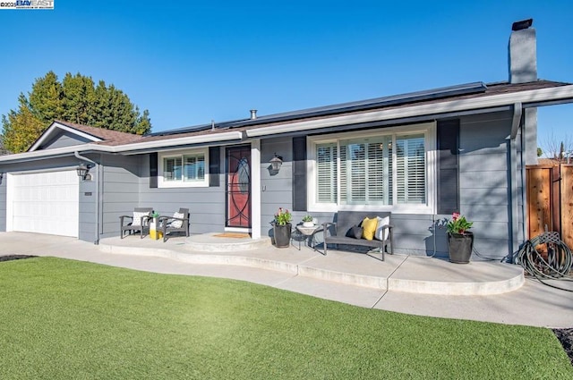 ranch-style home featuring solar panels, a garage, and a front lawn