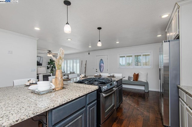 kitchen with appliances with stainless steel finishes, decorative light fixtures, dark hardwood / wood-style flooring, light stone counters, and crown molding