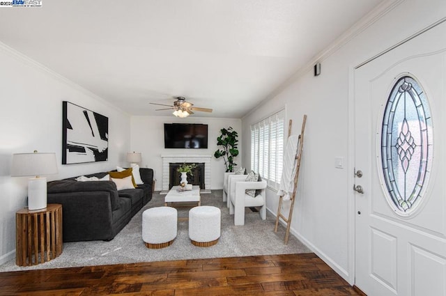 living room featuring ceiling fan, crown molding, a fireplace, and dark hardwood / wood-style flooring