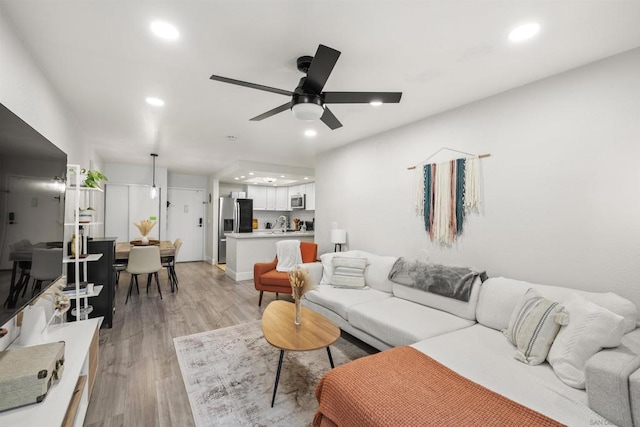 living room featuring ceiling fan and light hardwood / wood-style flooring