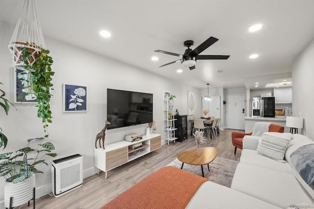 living room with sink, light hardwood / wood-style floors, and ceiling fan