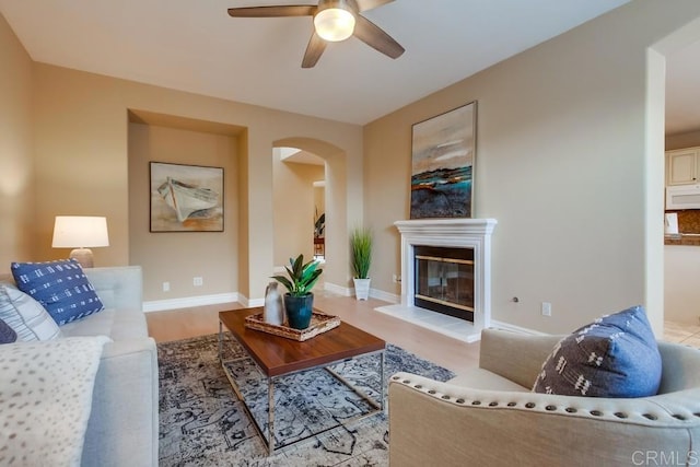 living room featuring light hardwood / wood-style flooring, a fireplace, and ceiling fan