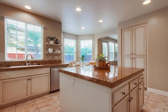 kitchen featuring a kitchen island, sink, stainless steel dishwasher, cream cabinets, and a healthy amount of sunlight