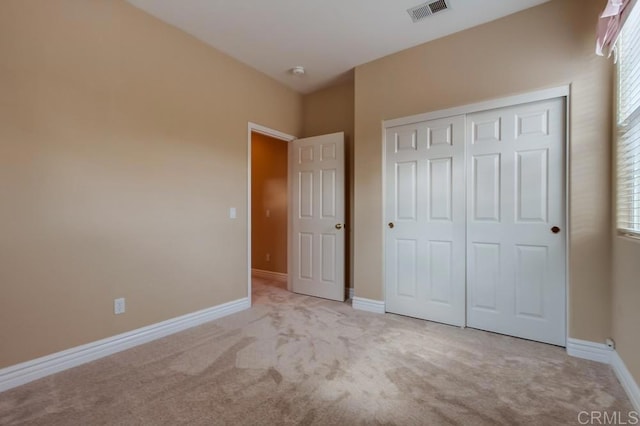 unfurnished bedroom with light carpet and a closet