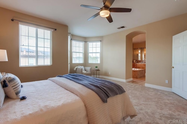 bedroom with multiple windows, ceiling fan, ensuite bathroom, and light carpet