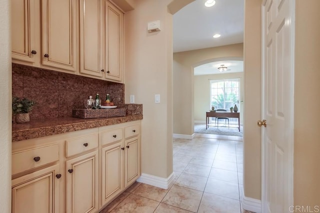 kitchen featuring backsplash, light tile patterned floors, and cream cabinetry