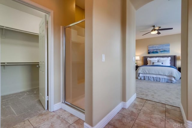 bathroom with tile patterned flooring, ceiling fan, and walk in shower