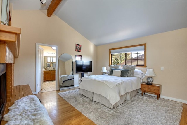 bedroom with beamed ceiling, high vaulted ceiling, ensuite bath, and light hardwood / wood-style flooring