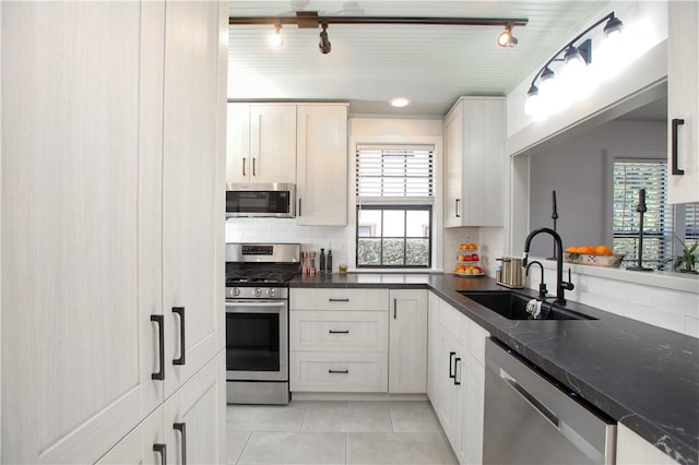 kitchen with stainless steel appliances, sink, light tile patterned floors, and white cabinets