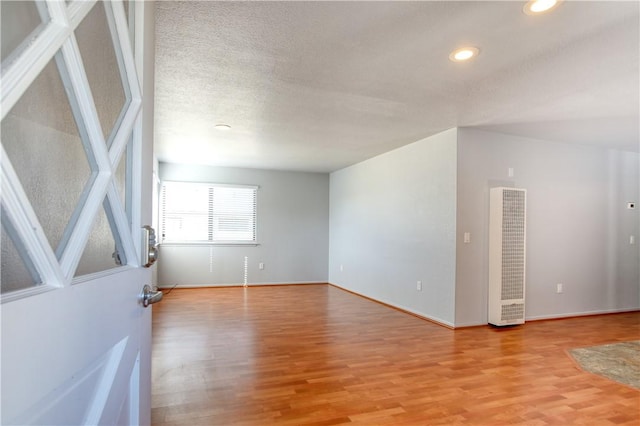 empty room with a textured ceiling and light wood-type flooring