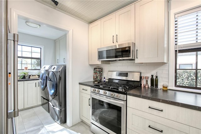 kitchen featuring light tile patterned flooring, stainless steel appliances, washing machine and dryer, and backsplash