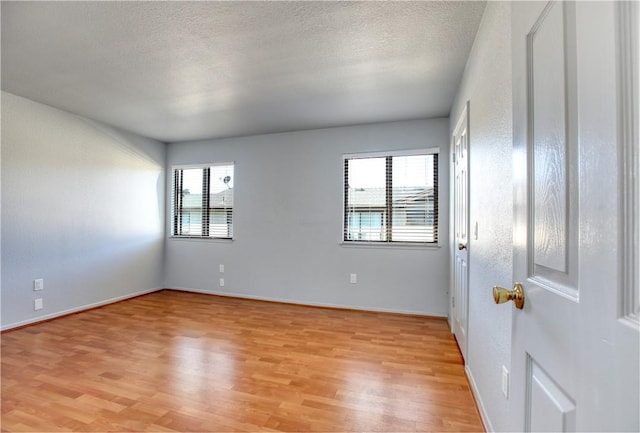 spare room featuring light hardwood / wood-style flooring and a textured ceiling