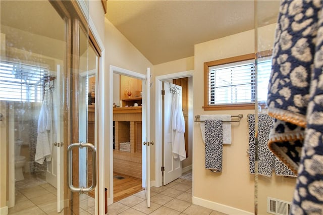 bathroom with vaulted ceiling, toilet, tile patterned flooring, and a wealth of natural light