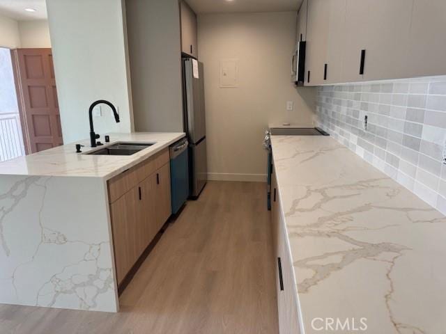 2501 W Sunflower Unit F12, Santa Ana, CA 92704 - kitchen with light stone counters, a peninsula, appliances with stainless steel finishes, light wood-style flooring, and recessed lighting