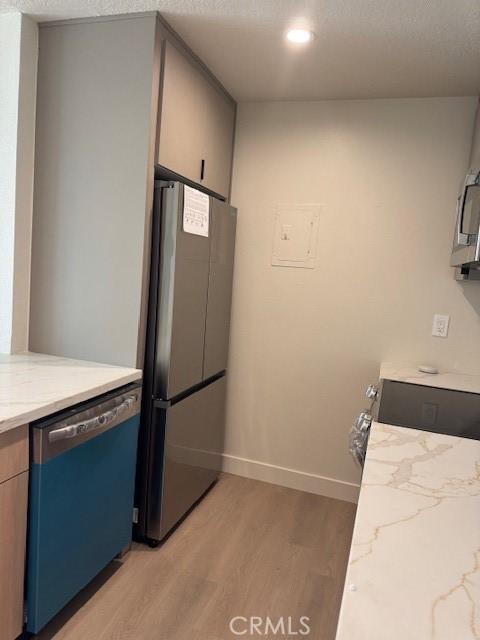 2501 W Sunflower Unit F12, Santa Ana, CA 92704 - kitchen with stainless steel appliances, light wood finished floors, light stone countertops, and recessed lighting