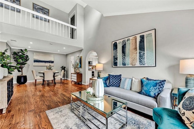 living room featuring crown molding, a towering ceiling, and wood-type flooring