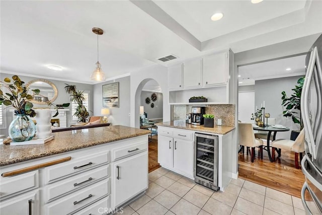 kitchen with stainless steel fridge, white cabinetry, hanging light fixtures, wine cooler, and light tile patterned flooring