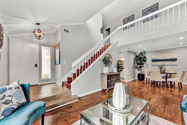 foyer featuring crown molding, high vaulted ceiling, an inviting chandelier, and hardwood / wood-style floors