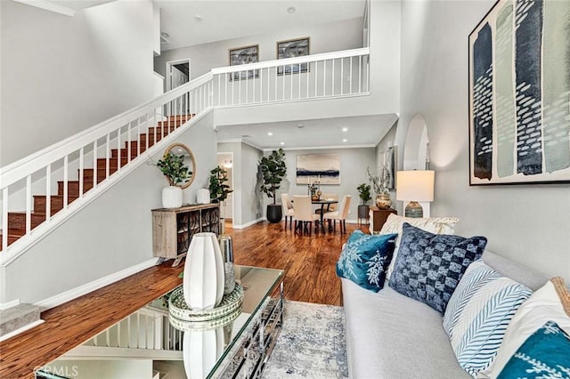 living room featuring hardwood / wood-style flooring, ornamental molding, and a high ceiling