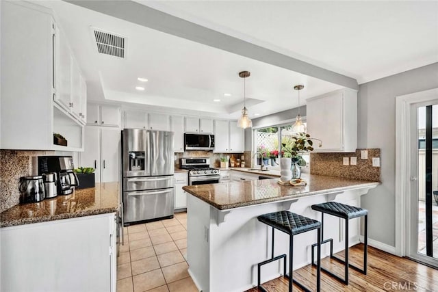 kitchen with white cabinetry, stainless steel appliances, and kitchen peninsula