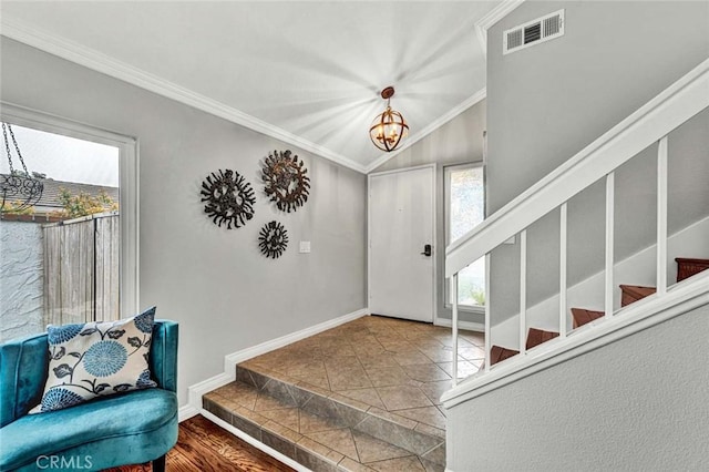 foyer featuring lofted ceiling, crown molding, tile patterned floors, and a chandelier