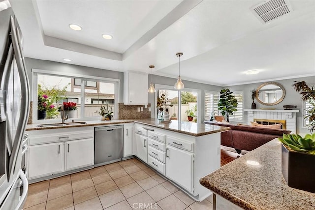 kitchen with sink, stainless steel appliances, white cabinets, decorative light fixtures, and kitchen peninsula