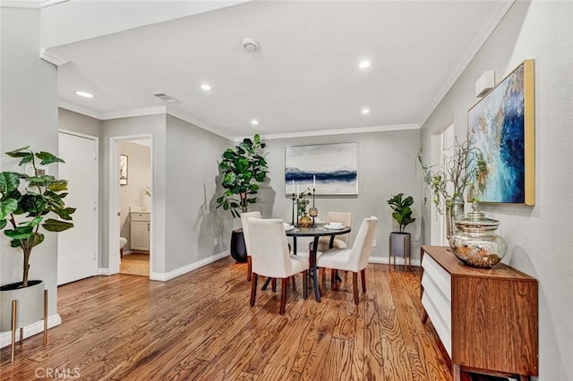 dining area with ornamental molding and light wood-type flooring